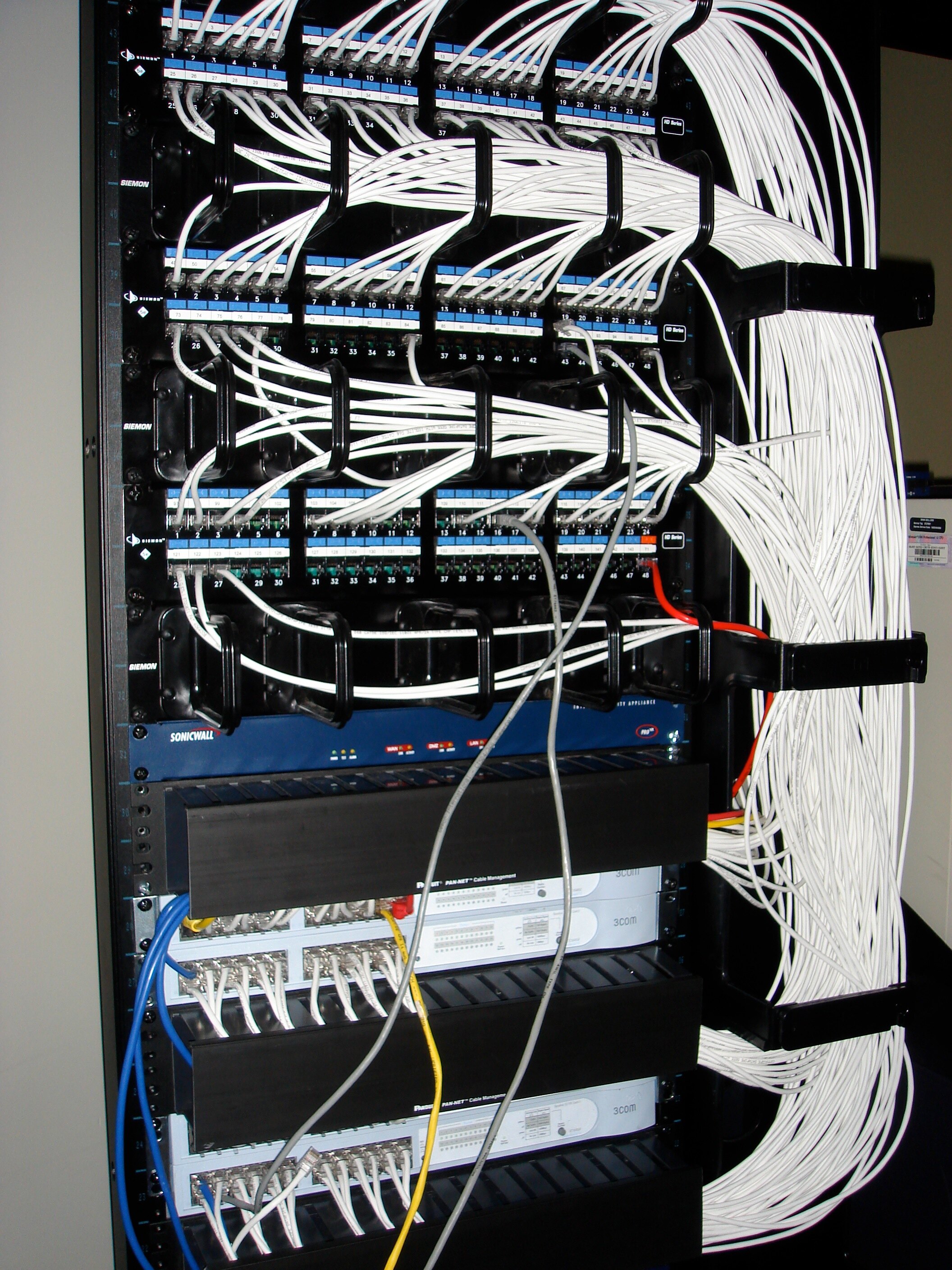 A hand-built server rack with labeled patch panels and carefully routed white network cables