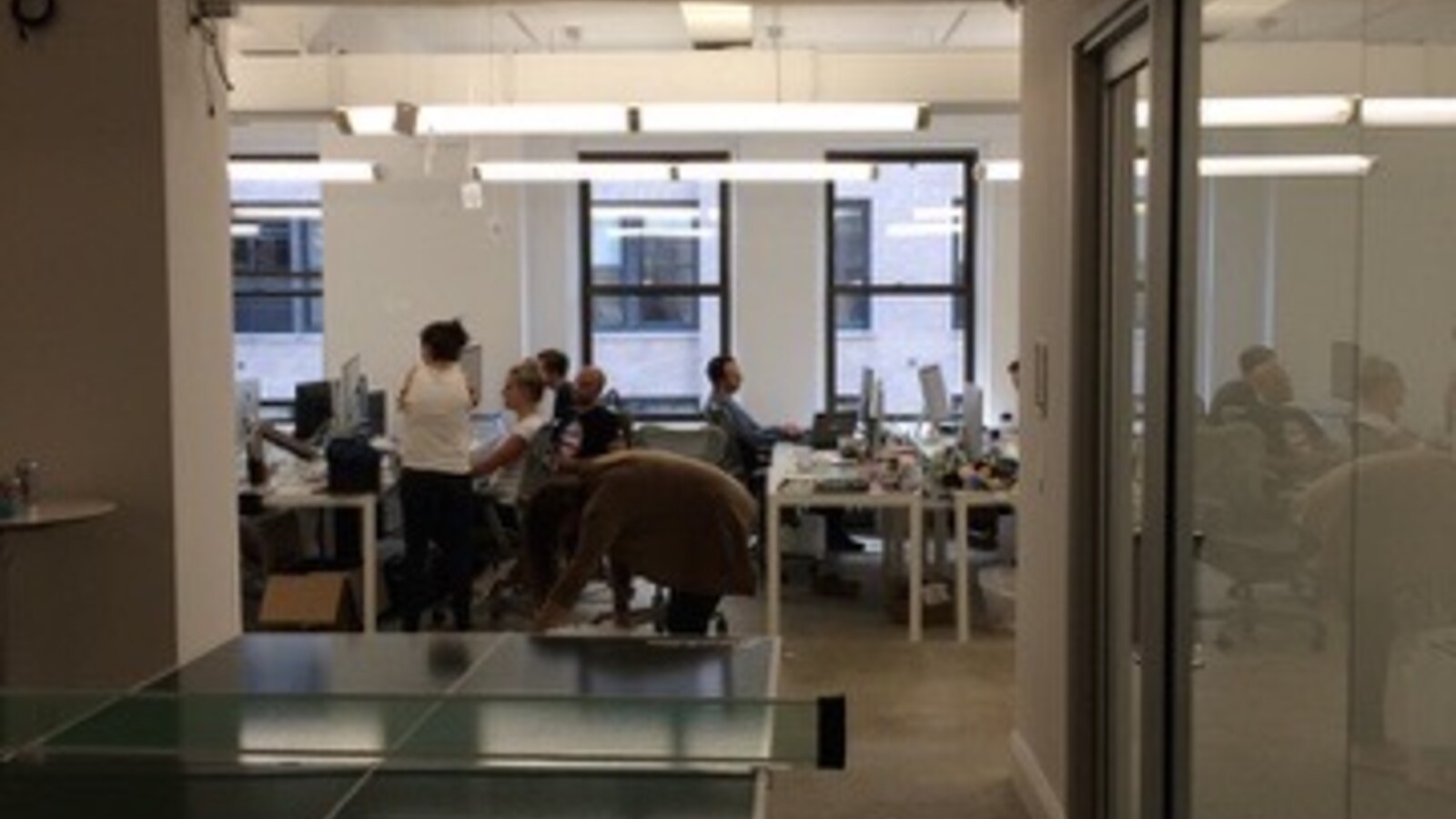 The Reonomy team working in the new office beyond a ping-pong table during the August 2015 hackathon