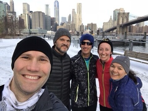 Chris Fischer smiling with four runners on a snowy Brooklyn waterfront with the Brooklyn Bridge behind them