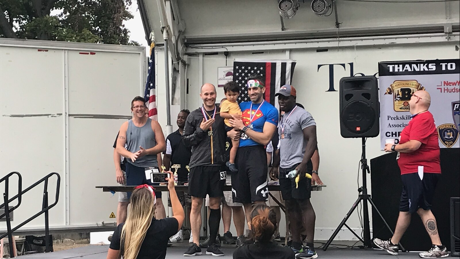 Chris Fischer holding up two fingers on the awards stage after the 2018 Peekskill Police and Fire 5K