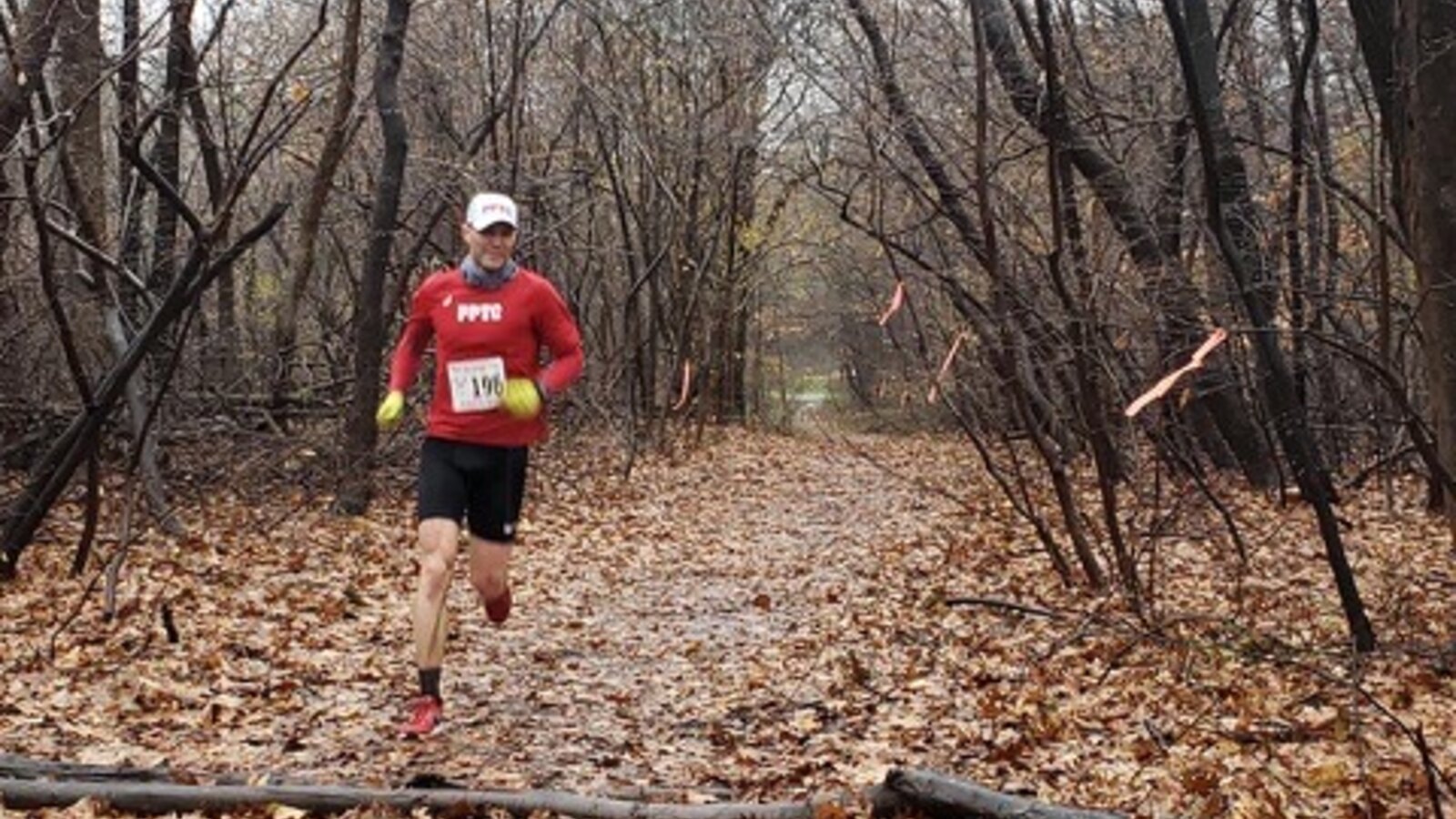 Chris Fischer in a red Prospect Park Track Club shirt running the muddy Beat the Bumble trail course