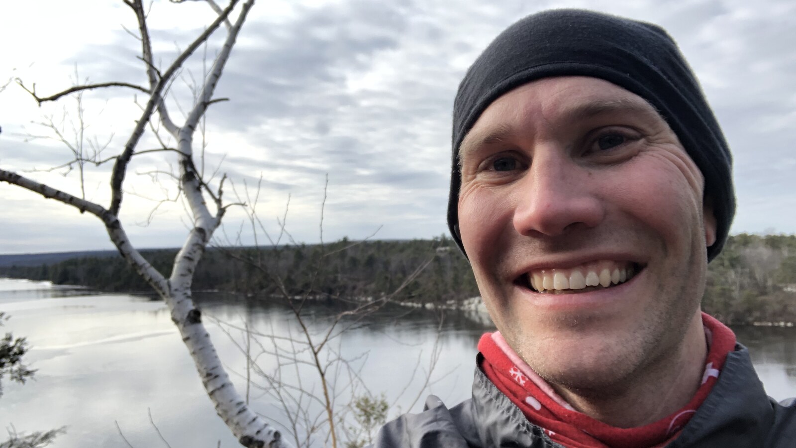 Chris smiling in winter running gear above frozen water in the Shawangunks