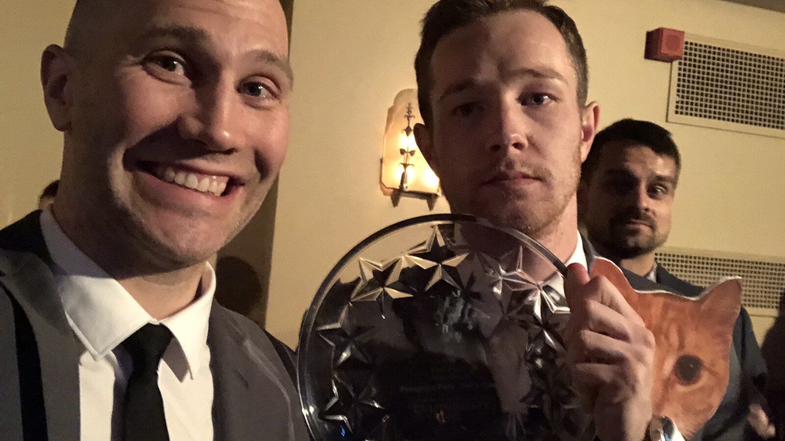 Chris Fischer smiling beside a Prospect Park Track Club teammate holding the large 2018 NYRR Open Men B first-place trophy
