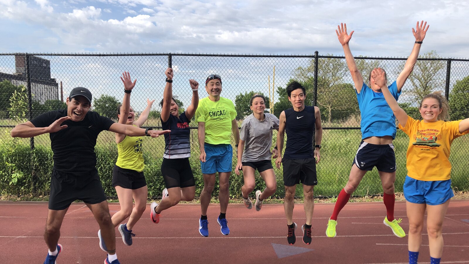 Eight runners jumping together during a track workout in Brooklyn
