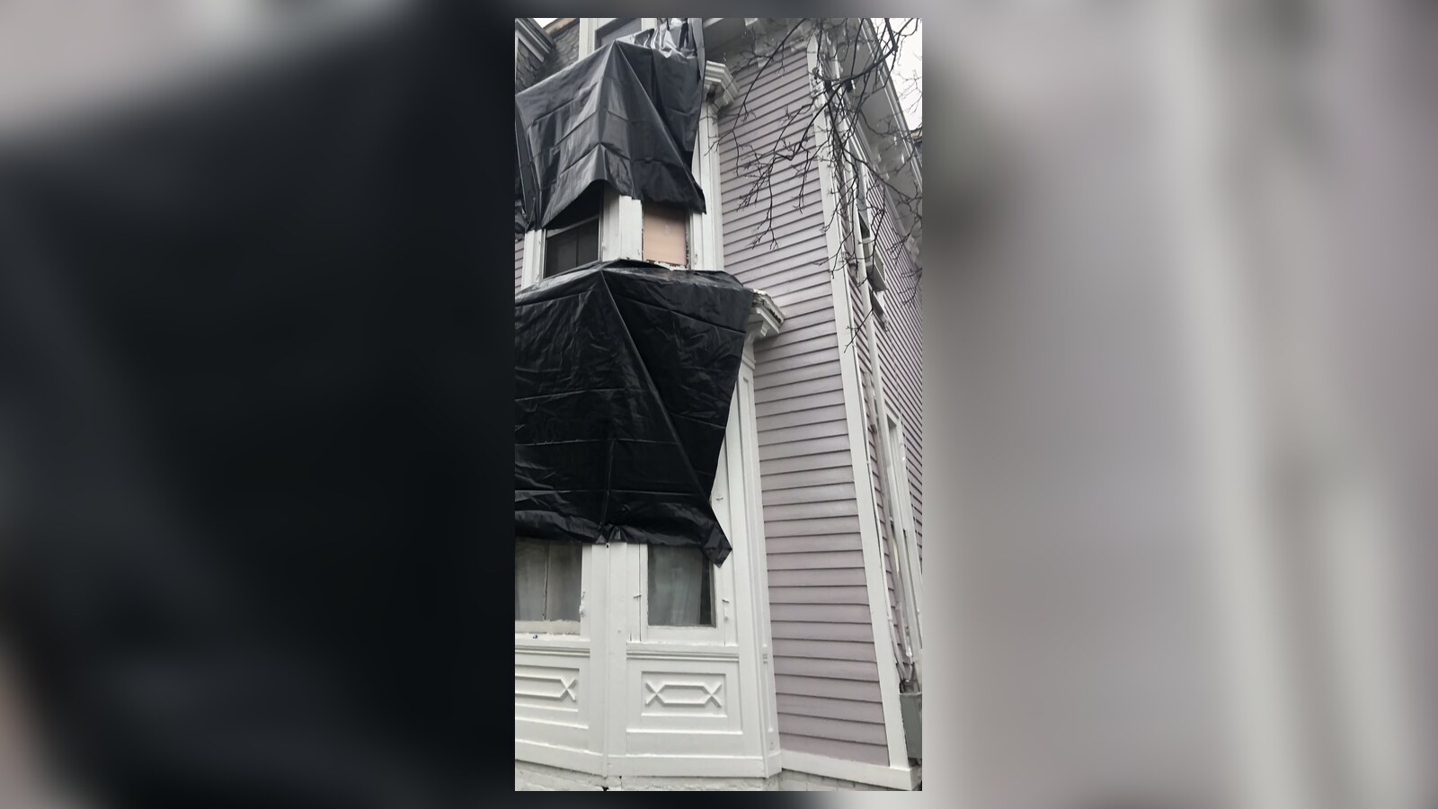 Black plastic tarps covering bay windows on Chris Fischer's Victorian after part of the gutters failed during lockdown