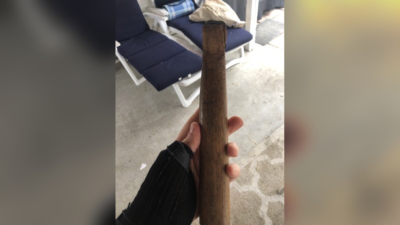 Chris Fischer's braced left wrist holding an old wooden axe handle