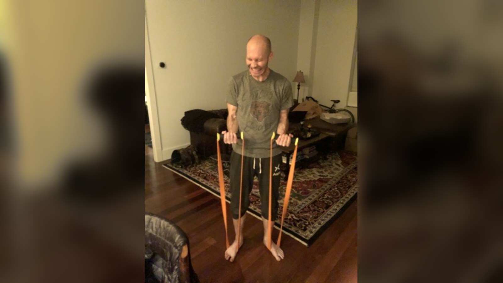 Chris Fischer smiling while trying a set of orange TRX resistance bands before starting at the company