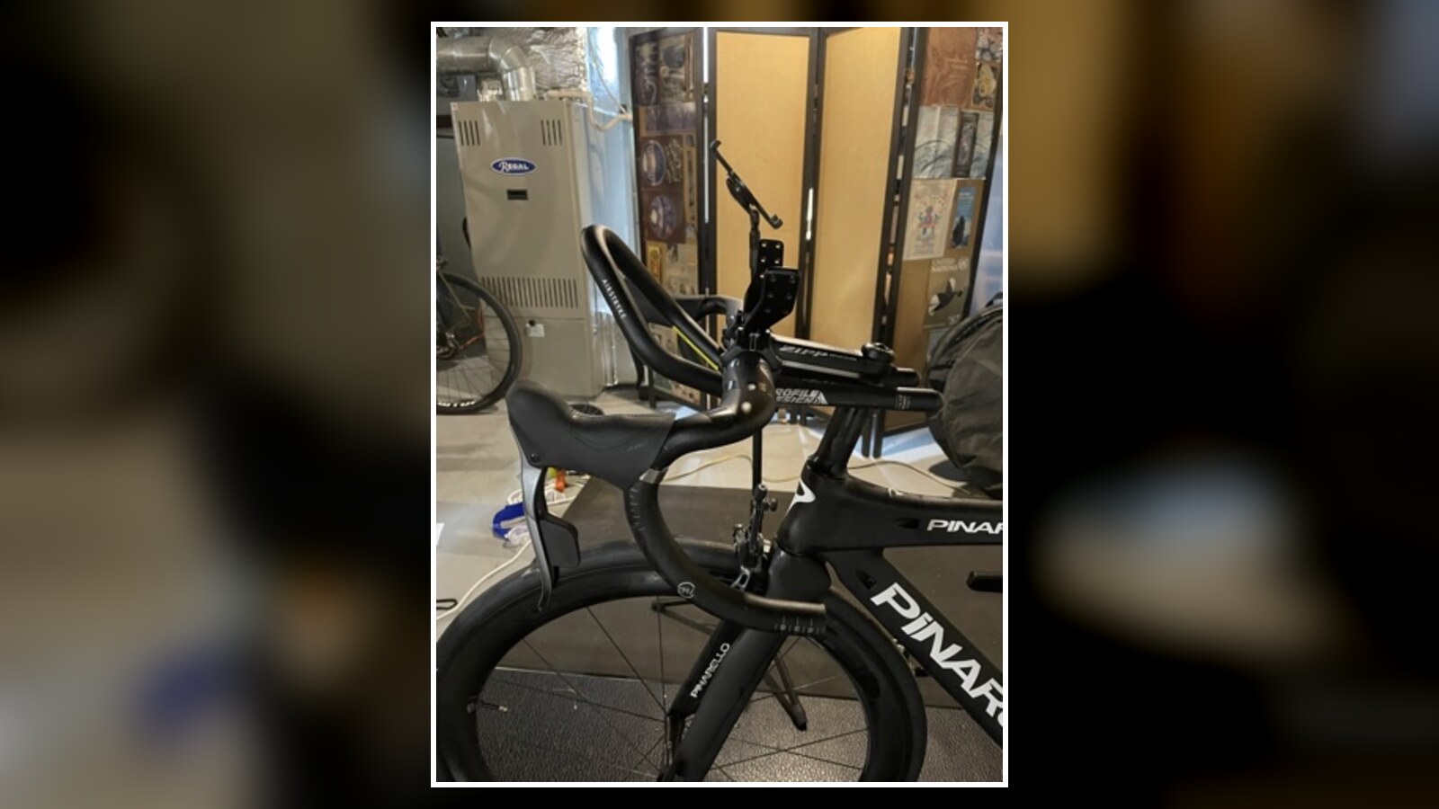 A Pinarello road bike mounted on an indoor trainer beside a window