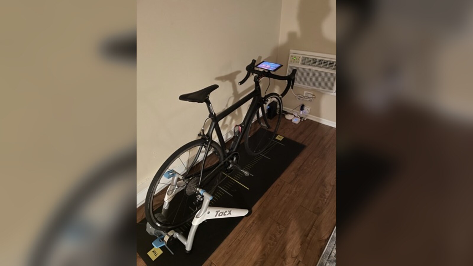 Chris Fischer's black race bike assembled on an indoor trainer in a Newport Beach apartment