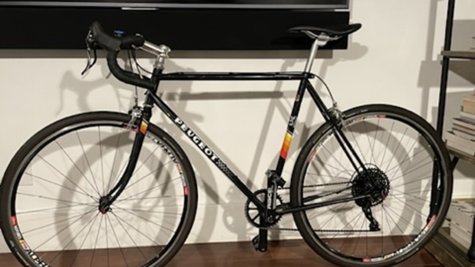 A steel Peugeot road bike rebuilt with a modern black one-by drivetrain