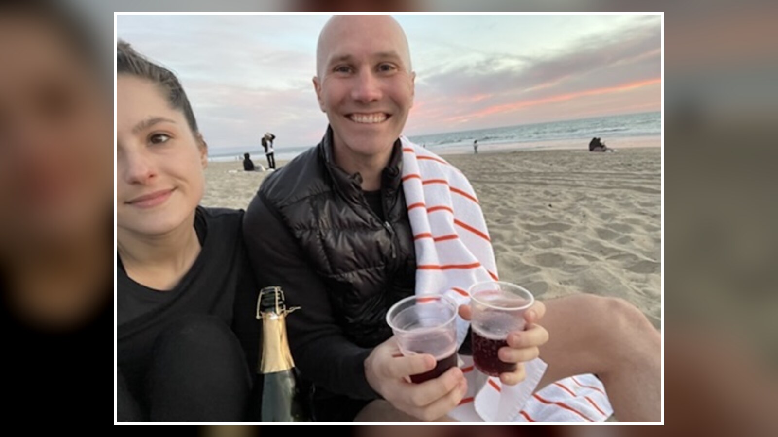 Amanda Wigand and Chris Fischer holding plastic cups at sunset on a California beach