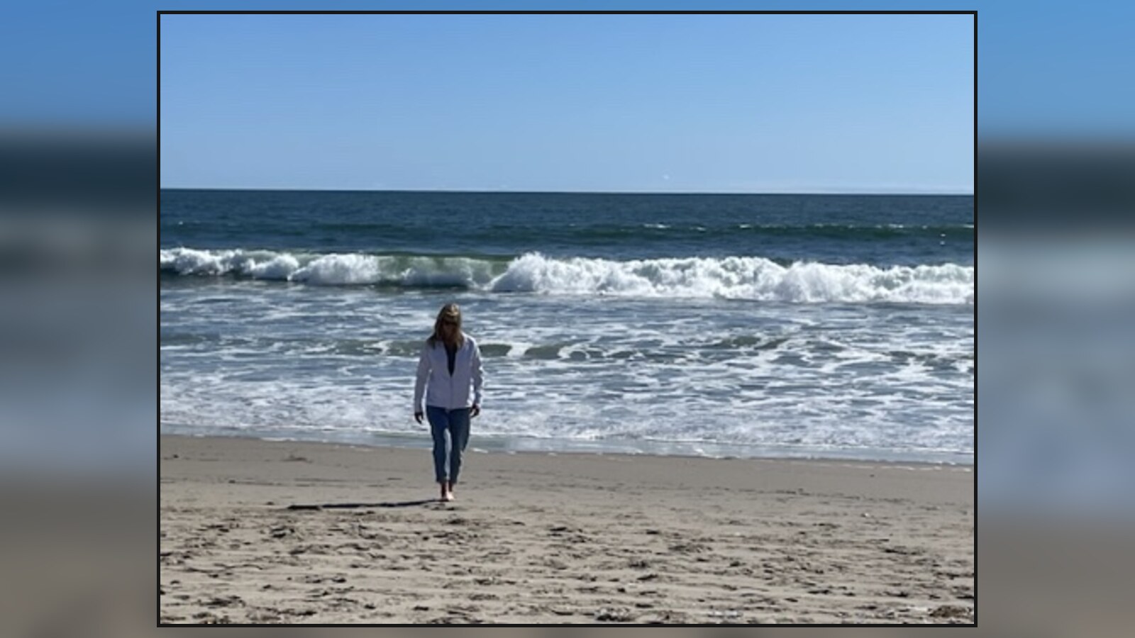 A woman walking up the beach during Chris's family trip to Santa Monica