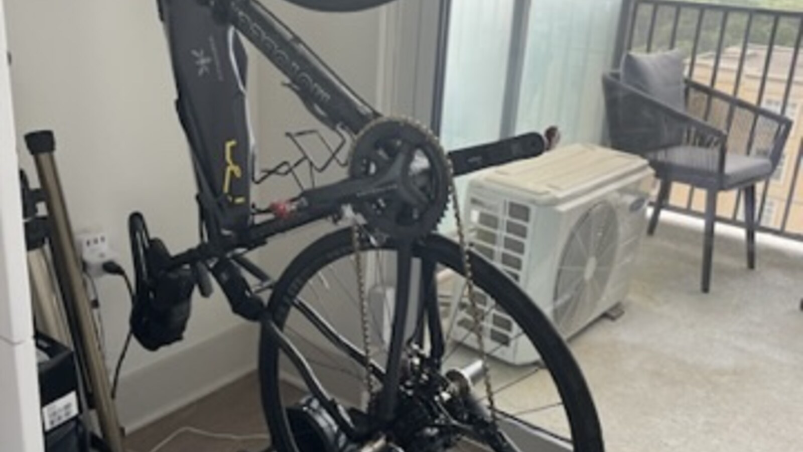 A road bike hanging above an indoor trainer beside a small Atlanta balcony