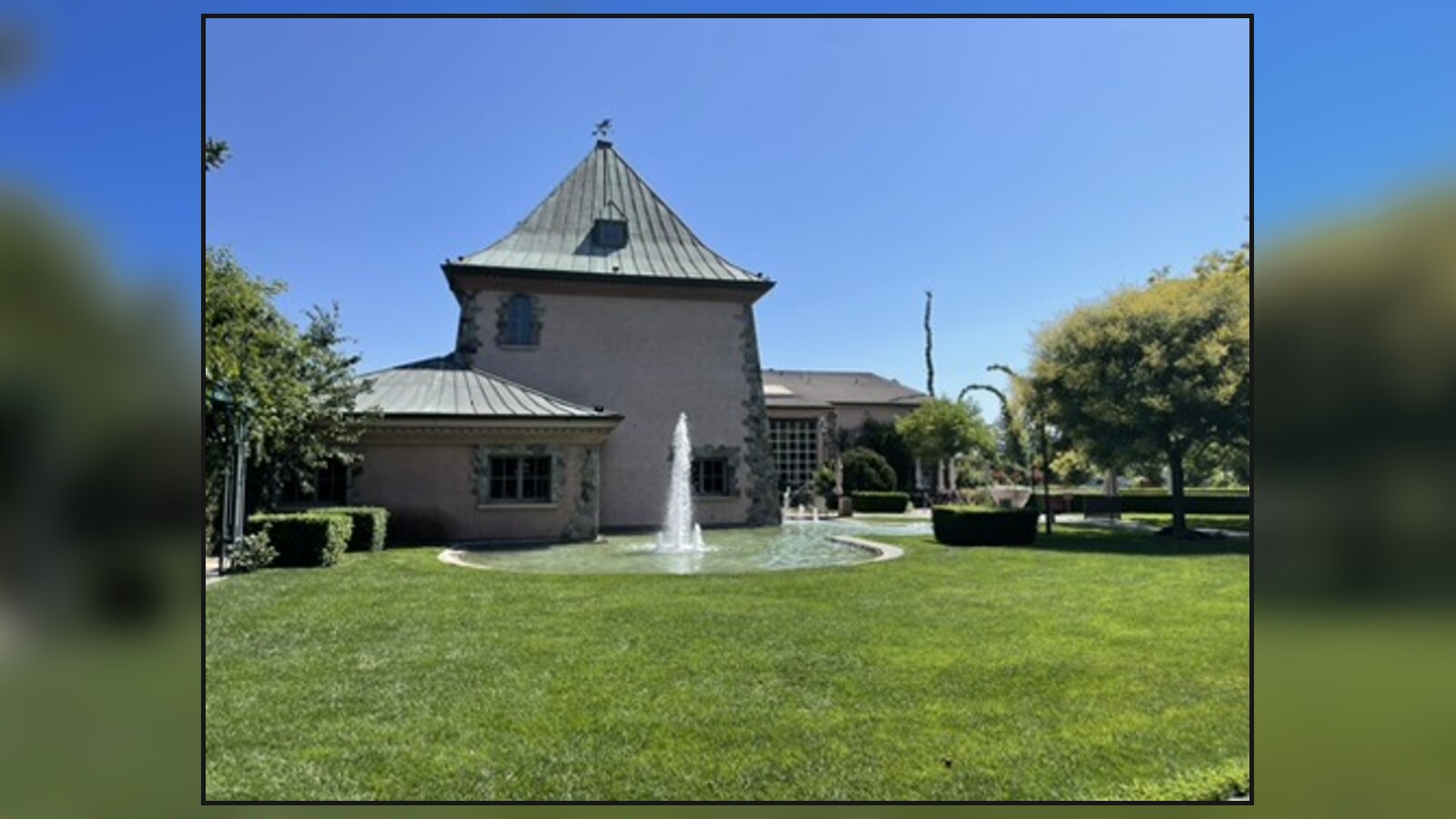 A Napa Valley winery building and fountain under a clear blue sky