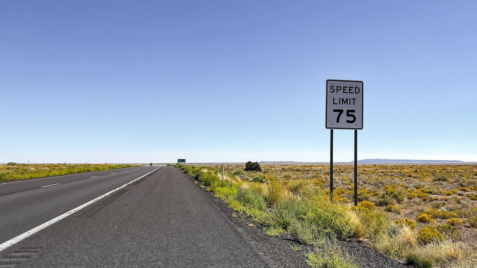 An empty Arizona highway shoulder beside a speed-limit-75 sign