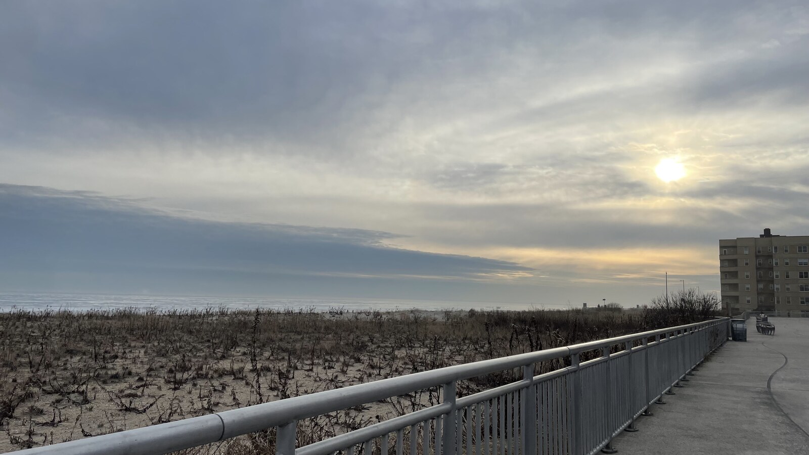 Winter sun over the Atlantic beside an empty stretch of the Rockaway boardwalk