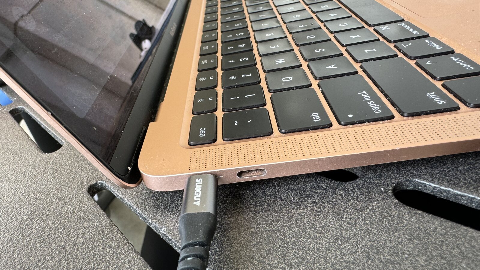 A close view of Chris's laptop and charging cable on a travel tray